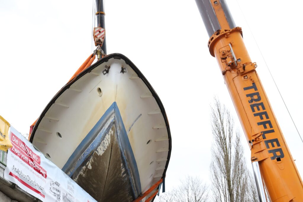Ein Kran hebt ein Schiff auf eine Brücke.