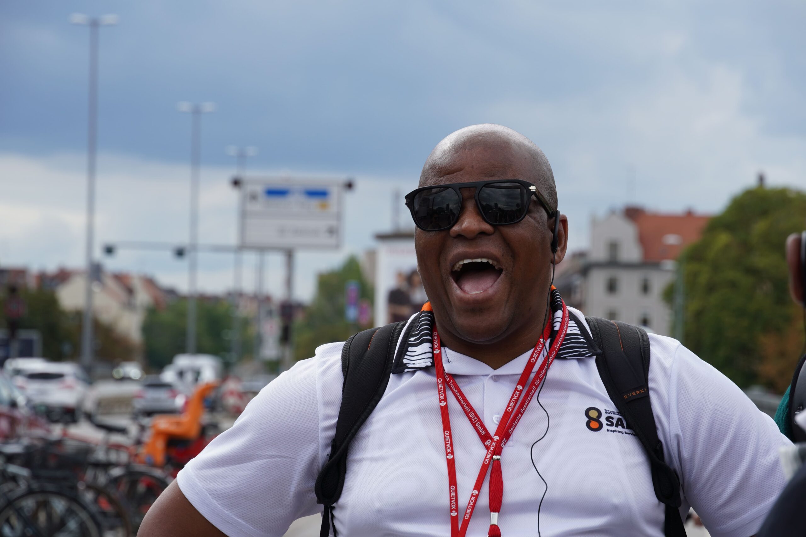 Ein Mann mit Sonnenbrille lacht in die Kamera.