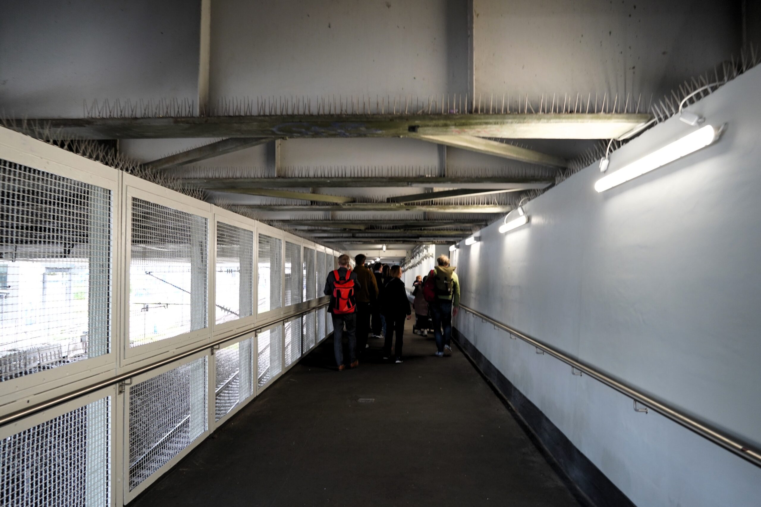 Gruppe von hinten in einem schmalen, niedrigen, schummrig beleuchteten Gang.